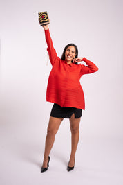 Mujer sonríe usando la blusa Aurora en color rojo. 