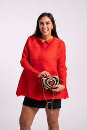 Mujer sonríe usando la blusa Aurora en color rojo. 