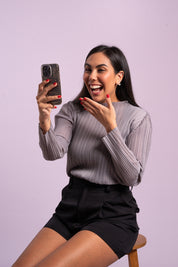 Mujer sonríe usando la blusa Audaz en color gris. 