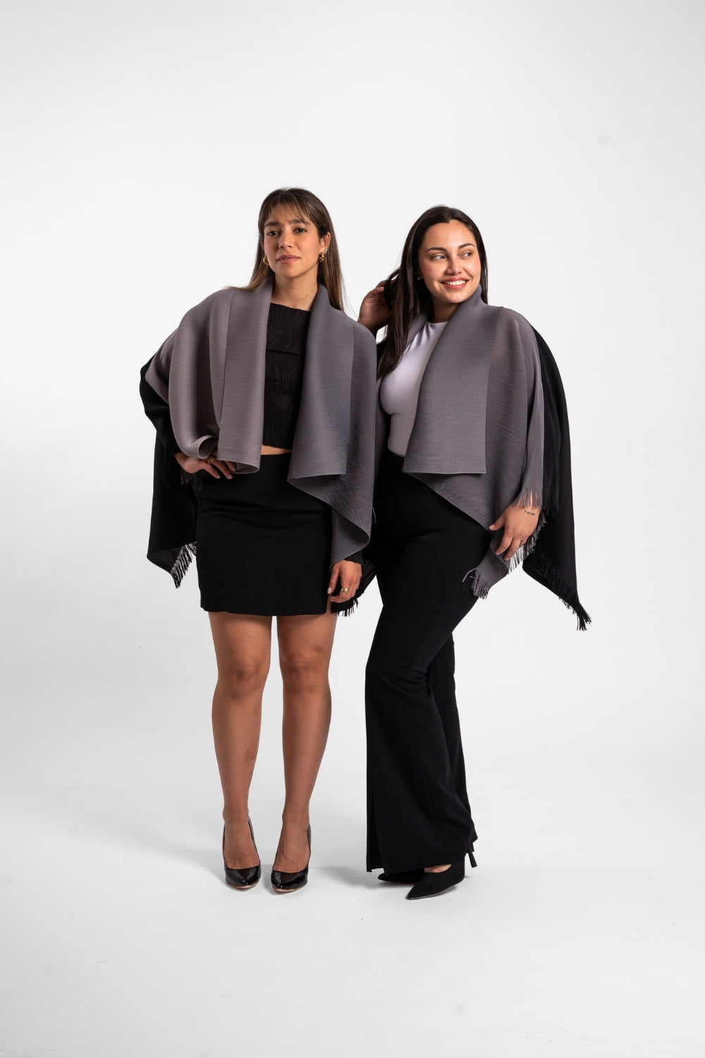 Dos mujeres usando la capa Visionaria en color negro y gris. 