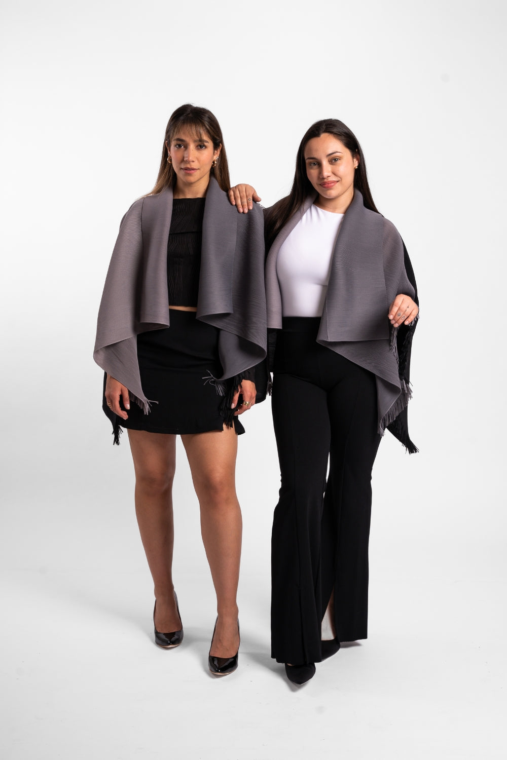 Dos mujeres usando la capa Visionaria en color negro y gris. 